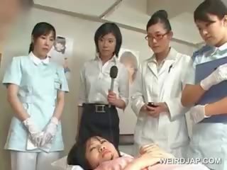 Azijietiškas brunetė lassie pučia plaukuotas varpa į as ligoninė